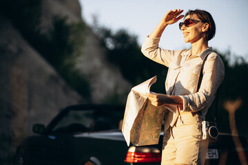 Woman road tripping by cabriolet and looking at the map