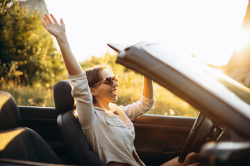 Woman sitting in car cabriolet and waving hands