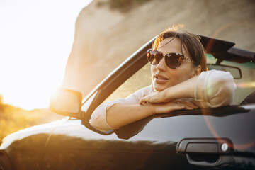 Woman road tripping by her car cabriolet