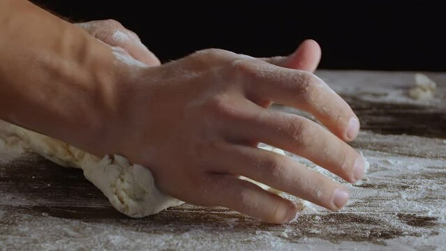 Male hands divide baking dough into shares on a board sprinkled with flour