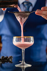 Straining a Pink Gin Cocktail