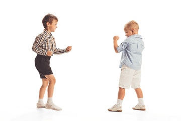 Portrait of two little boys, children playing together isolated over white studio background. Boxing round
