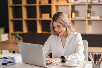 Fototapeta na wymiar Beautiful Asian portrait businesswoman manager smile workingin office with a laptop in the modern office sitting online marketing financial communication.