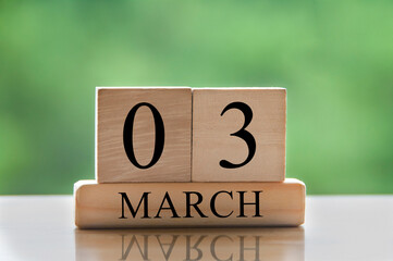 March 3 calendar date text on wooden blocks with blurred park background. Copy space and calendar...