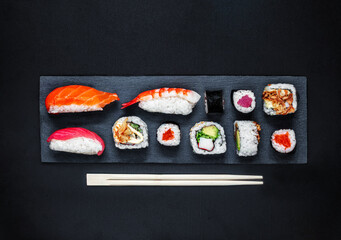 Sushi set on a black slate  background. Japan restaurant menu. Sushi with salmon, tuna and avocado. Top view.