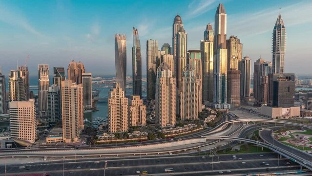 Dubai Marina highway intersection spaghetti junction night to day transition timelapse. Illuminated tallest skyscrapers on a background. Aerial top view from JLT district before sunrise