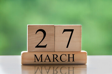 March 27 calendar date text on wooden blocks with blurred park background. Copy space and calendar concept