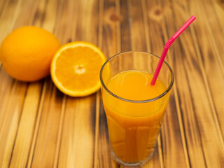 Ripe bio oranges and a glass of fresh squeezed orange juice on wooden background