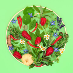 Edible flowers herbs and spice health food seasoning abstract design. Healthy natural summer ingredients for culinary use on green with circular wooden frame. 