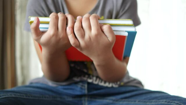 child girl holding many colorful notepad sited on chair 