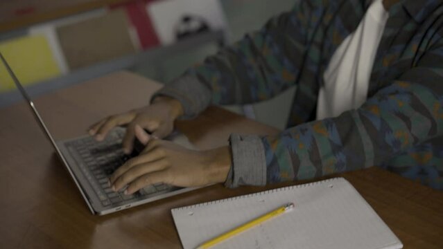 Close up tilt and pan of a Native American male student typing in class while he nods.