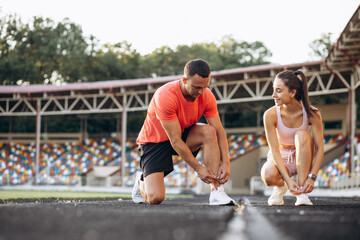 Man and woman tiying laces on their sneakers