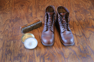 a pair of men's leather shoes brown boors, a shoe brush and shoe cream, mink fat on a wooden floor