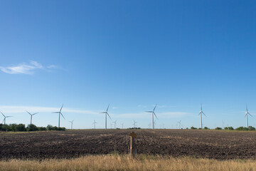 Fototapeta na wymiar Windmill farm of wind turbines in rural Oklahoma or Texas producing electricity with a renewable resource wind