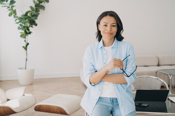 Portrait of confident freelancer or businesswoman, which leans to the workstation at home office.