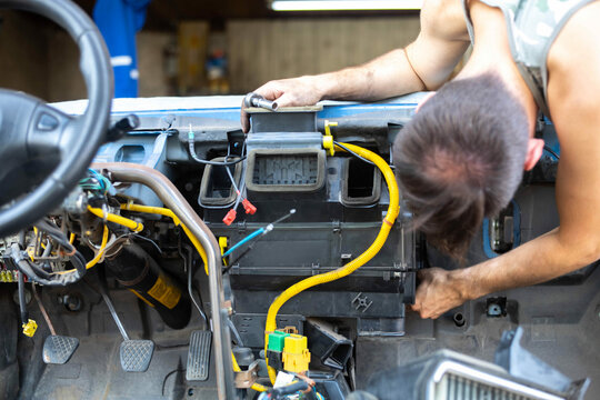 man disassembles the car interior console to repair the interior heater and electrics.