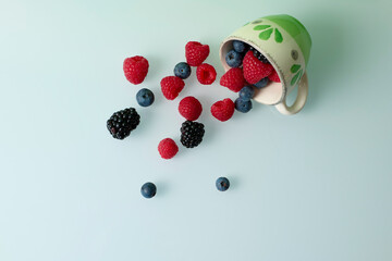 Cup with red fruits on green background
