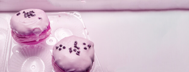 Two delicious donuts with icing sugar and chocolate chips in a transparent plastic container, a...
