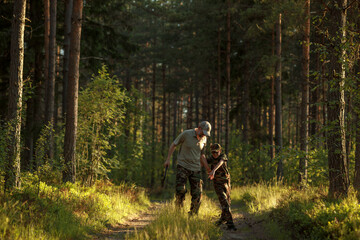 Obraz premium Father and son in military clothes spending time together in the woods. The concept of adventure, travel, tourism and camping