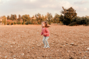 Naklejka na ściany i meble Cute little girl wear jumper walking in field, enjoying freedom and fresh air.