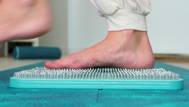 Get off the nails. Sadhu wooden blue board with nails, female feet step on sharp nails for meditation, foot relaxation, acupuncture tool. Exercises for relaxation and harmonization