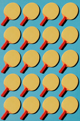 on a blue background a lot of yellow table tennis rackets with red and orange, no person 