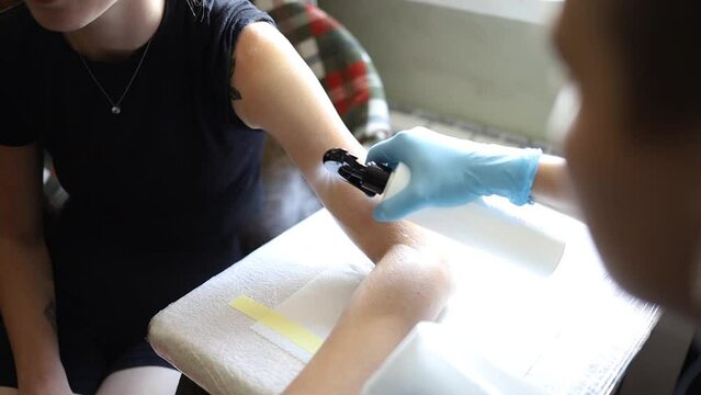 Tattoo artist makes a tattoo woman on a arm, works in studio. Tattoo art on body.