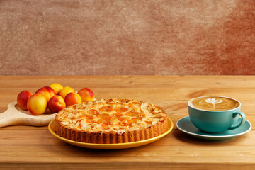 Homemade pie with apricots and cup of coffee cappuccino on wooden table. Copyspace.
