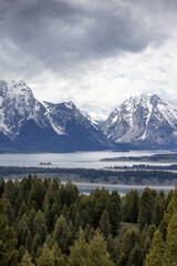 Lake surrounded by Trees and Mountains in American Landscape. Spring Season. Jackson Lake, Grand Teton National Park. Wyoming, United States. Nature Background.