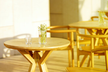 Chamomile flowers stand in a glass vase on a wooden table in an restaurant