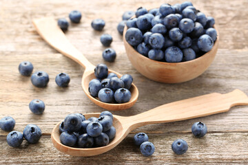 Spoons and bowl with tasty fresh blueberries on wooden table