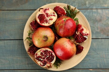 Delicious ripe pomegranates on blue wooden table, top view