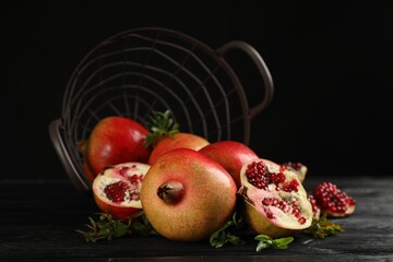 Delicious ripe pomegranates on black wooden table