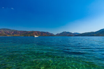 The Boat on the sea surface, feeling of calm and freedom. View from the boat to the blue bay and the green mountains of the island on a sunny day. Travel - image.