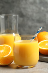Glass of orange juice and fresh fruits on grey table