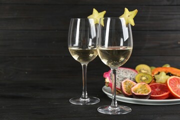 Delicious exotic fruits and wine on black wooden table. Space for text