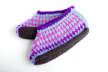 Purple knitted socks with geometric patterns on a white background. The concept of warm clothes made of woolen thread