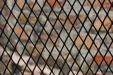 Mesh fence on stone background outdoors