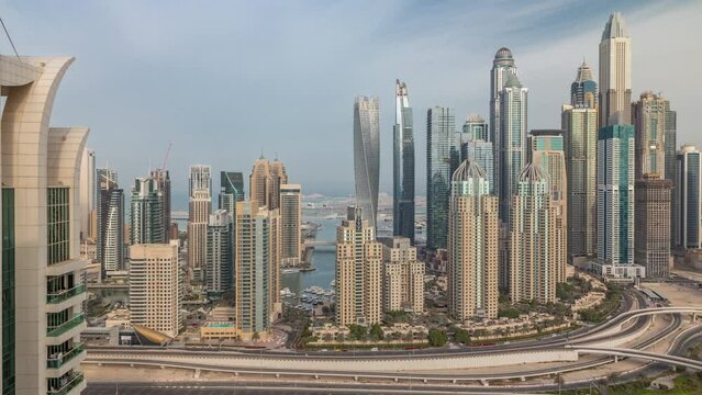 Skyscrapers of Dubai Marina with highest residential buildings morning timelapse. Aerial top view from JLT district during sunrise. Cloudy sky