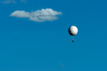 white balloon flies with passengers across the blue sky, background for design