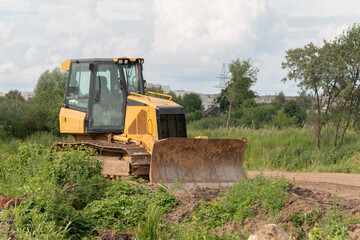 Crawler bulldozer clears the ground with a metal shield. Landscaping. Road construction works. The caterpillar bulldozer is used for layer-by-layer movement of soils.