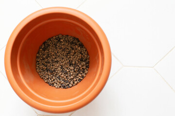 Flowerpot with expanded clay for planting plants on a white tile top view.