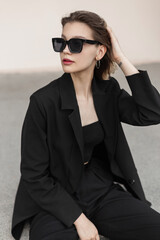 Fashionable urban fresh beauty woman with trendy sunglasses in black business elegant clothes with...