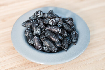 Kamchatka berry / haskap berry / honeysuckle (Lonicera caerulea) fruits, freshly picked and arranged on a small gray plate, standing on a wooden board. © Łukasz T.