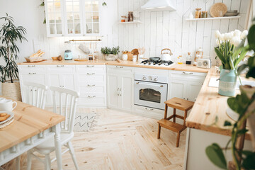 Modern white Scandinavian style kitchen with wooden worktop filled with kitchen accessories....