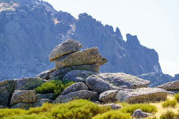 Fototapeta na wymiar Large rocks stacked with strange shapes with large rocky mountain in the background in the Community of Madrid, Spain.