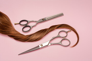 A strand of light brown hair with a pair of hairdressing scissors on a pink background.
Hairdressing services