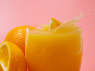Orange and orange slice. Orange Juice Splashing. Orange on a pink background.