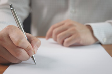 Closeup of businessman hand holding pen and singing a signature on paper. Business contract...