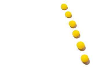 a strip of yellow round candies on a white background, selective focus